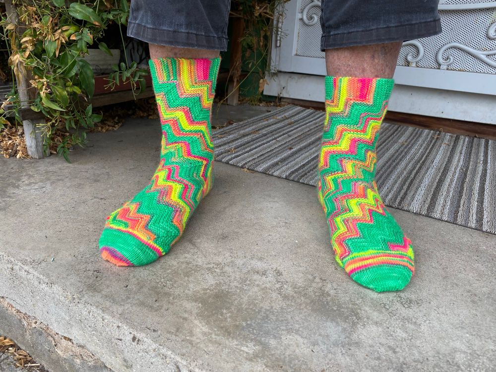 Very colorful socks on a man‘s foot. Colors are neon - green, yellow, orange, pink
The #socks were a #sock madness pattern