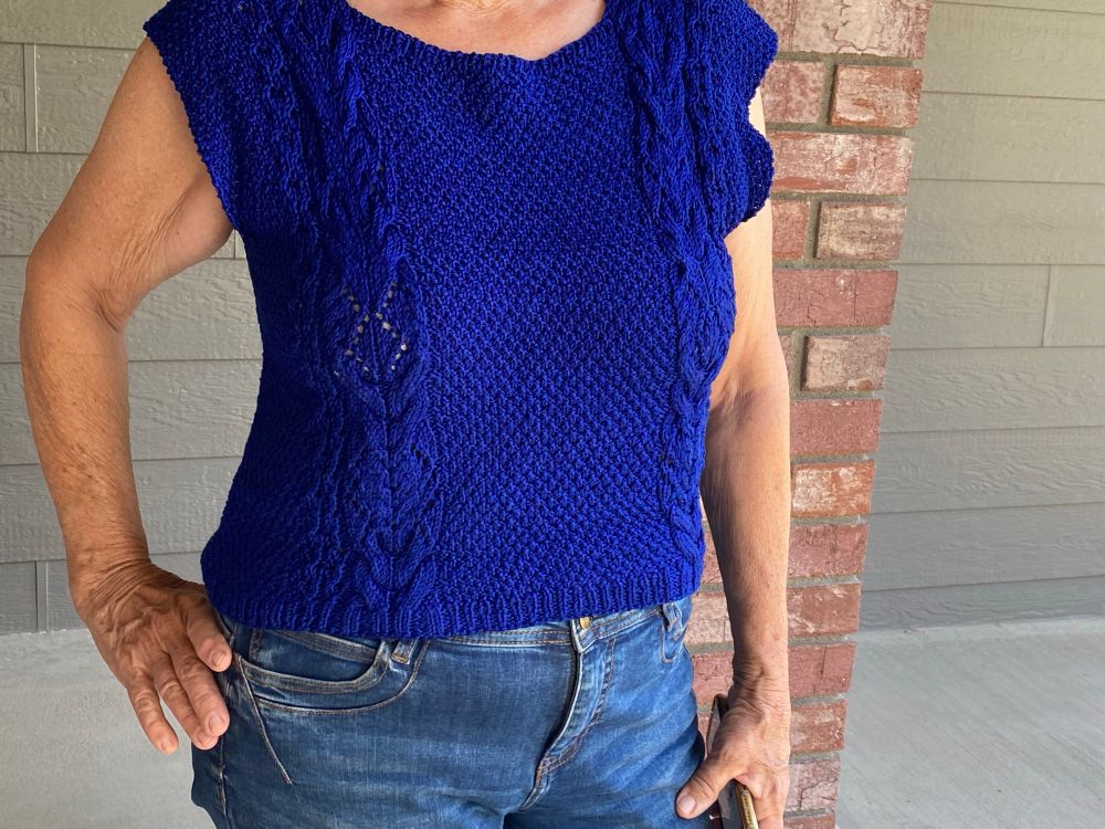 A Bluesky knitted garment with moss stitch and bands of cables on either side. This is the front view