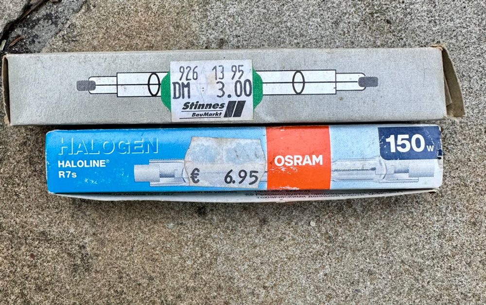 Bild zweier Halogen Leuchtmittel. Die obere Packung ist mit dem Preis 3 DM ausgezeichnet, die untere mit 6,95€.