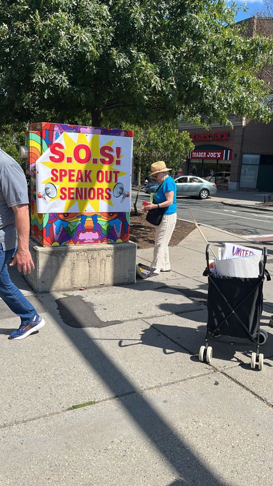 A sign being put up that says SOS! SPEAK OUT SENIORS 