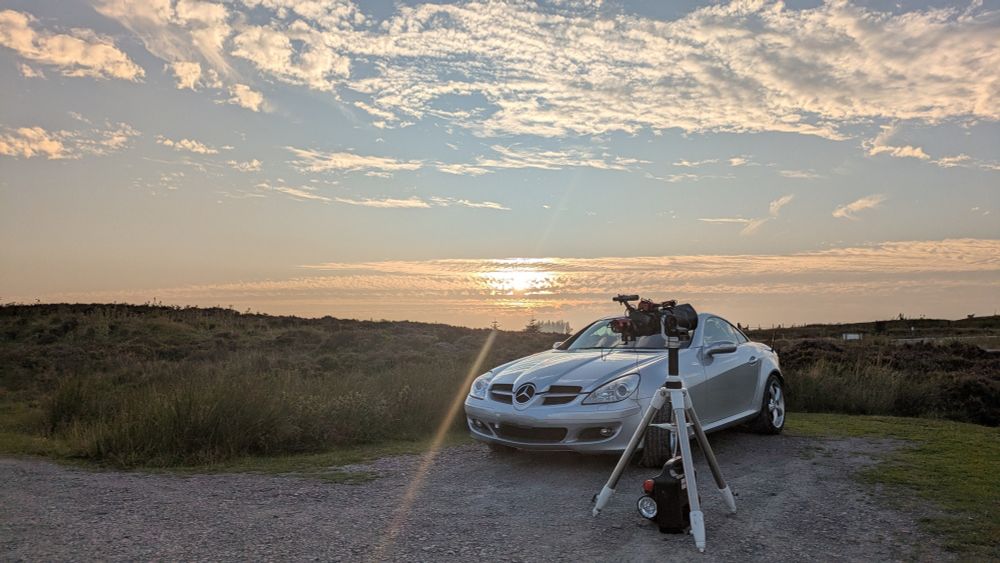 Car with sunsetting in the background with telescope in the foreground