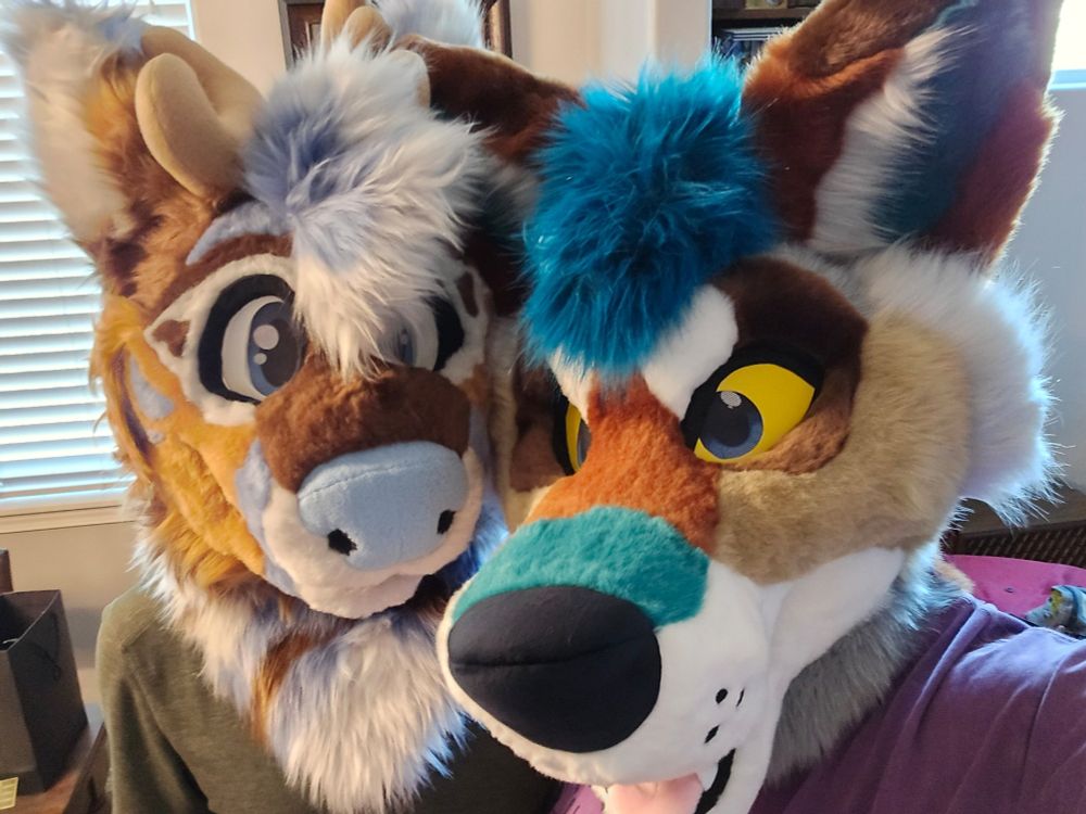 Two absolute cornball wearing their new fursuit heads. A Deer on the left, and a coyote on the right.