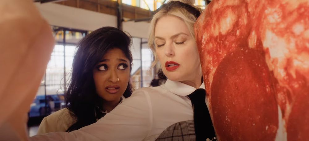 Elaine Hendrix closes her eyes in frustration alongside a giant pizza slice and a coworker in the "Freakier Friday" trailer