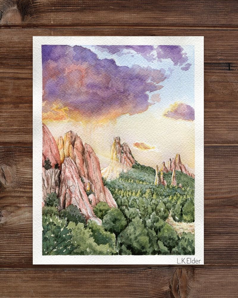 Watercolor painting of Garden of the Gods in Colorado Springs, Colorado. Light shines from behind the red rocks while a big purple thunder cloud rains down into the light. 