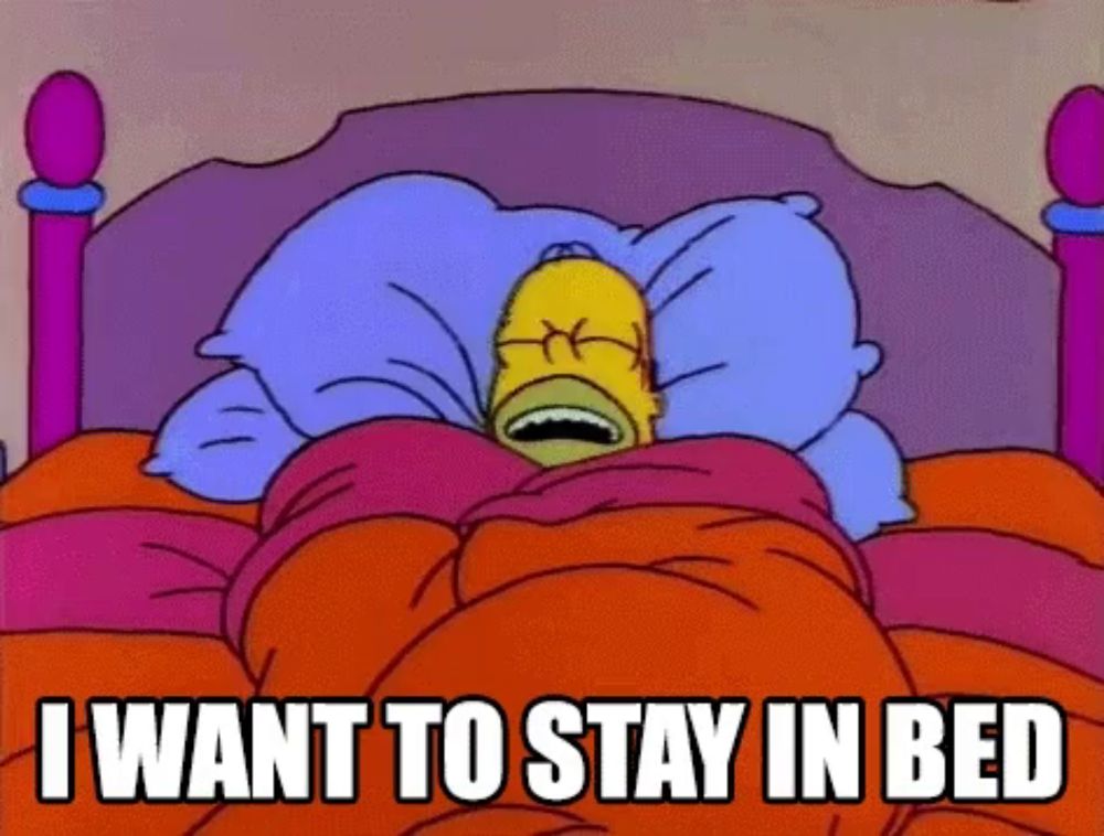 a cartoon of homer simpson laying in bed with the words " i want to stay in bed " above him