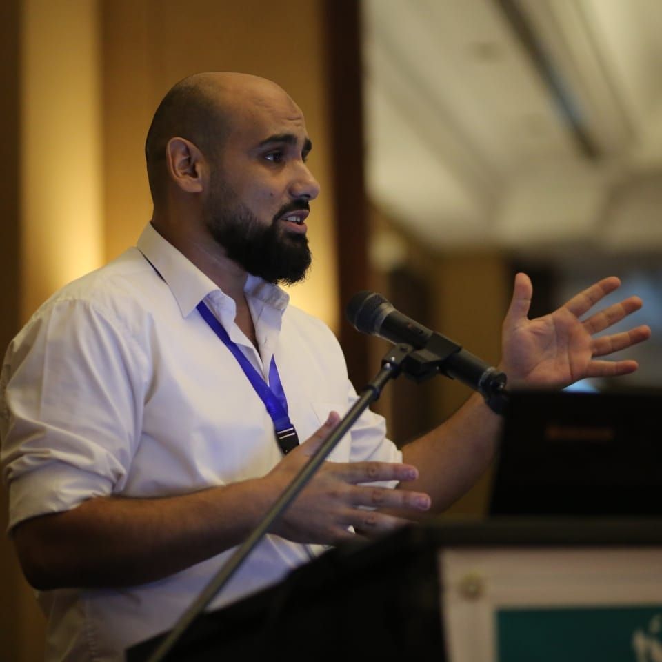 MSF physiotherapist Abed speaking at a podium during an event.