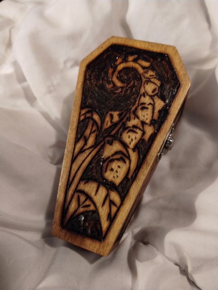 A small coffin box with foxglove flowers pyrographed onto the top.