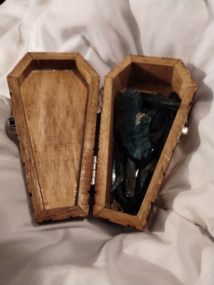 Same small coffin box open showing a bunch of shard crystals of dark green/black vivinite crystals.