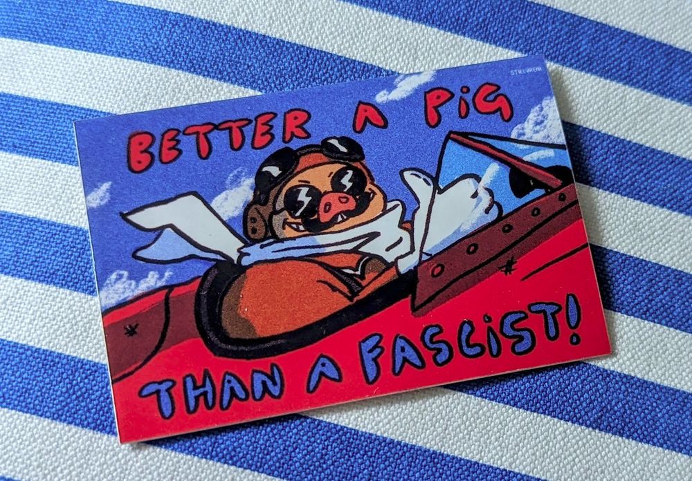 Porco from Porco Rosso in his plane, grinning and giving a thumbs up. Handwritten text reads BETTER A PIG THAN A FASCIST! The artwork is signed STILLVRENI