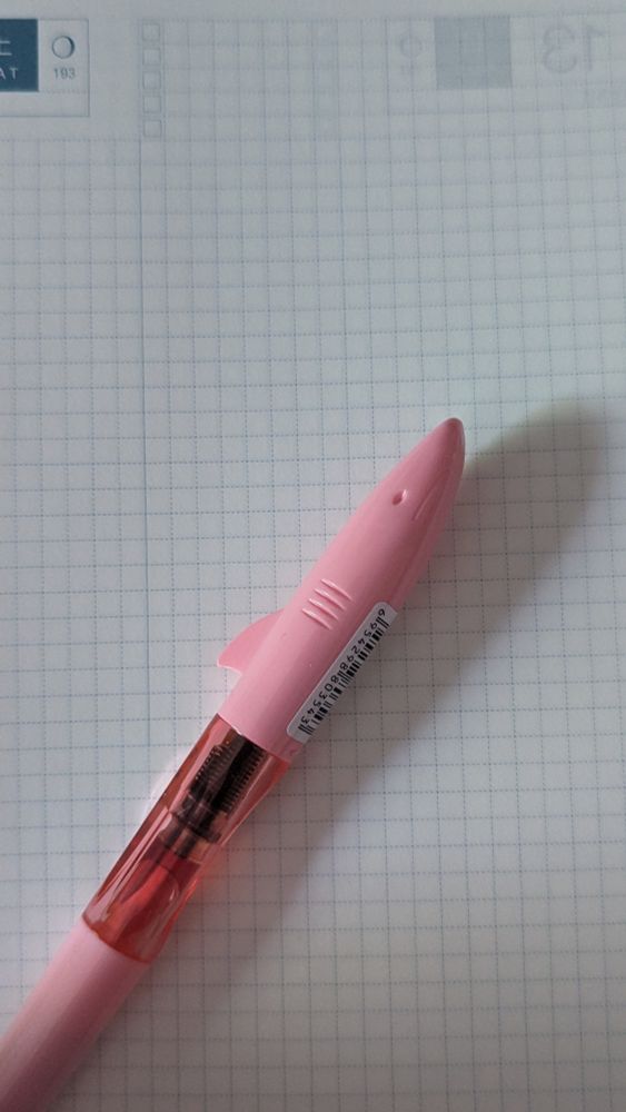 A pink shark-shaped plastic pen on a hobonichi journal page. It's a Jinhao 993 model.