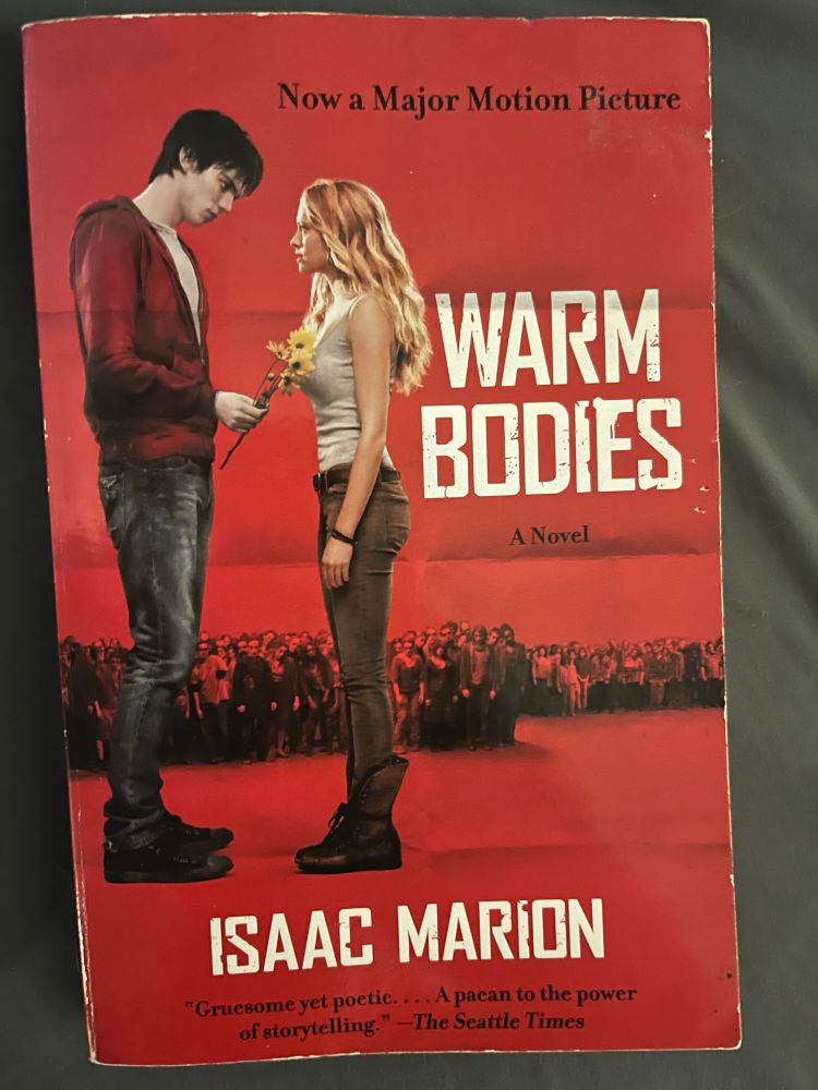 Cover of Warm Bodies by Isaac Marion. Zombie boy handing flowers to living girl with zombie masses in the background just standing watching.
