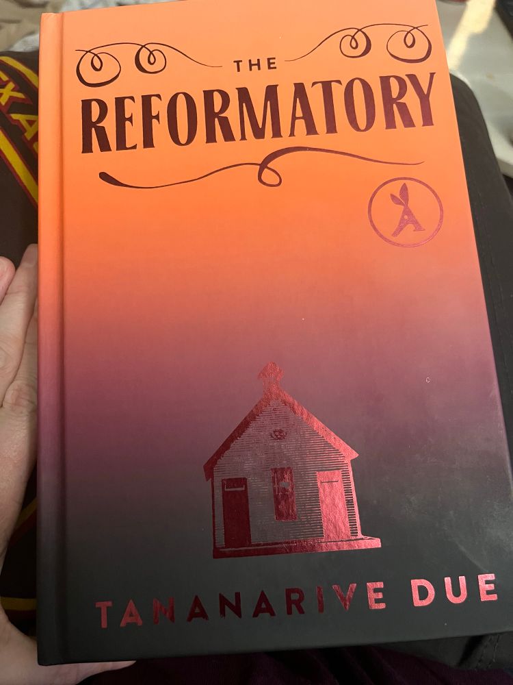 Cover of book The Reformatory by Tananarive Due. Orange to black ombré with line drawing of a schoolhouse.