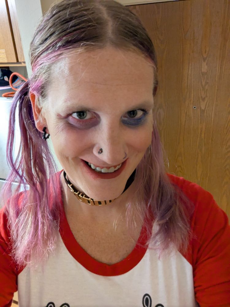 Callie dressed up as Harley Quinn. Wearing a shirt that says Mommy's Lil Monster, a collar that says Puddin, blue and red sequin panties, fishnets with skulls and thigh high boots. 