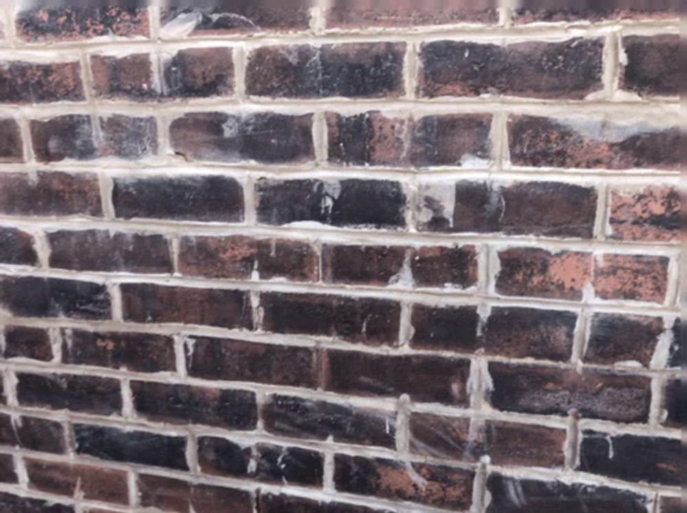 a close up of a brick wall with a few white bricks