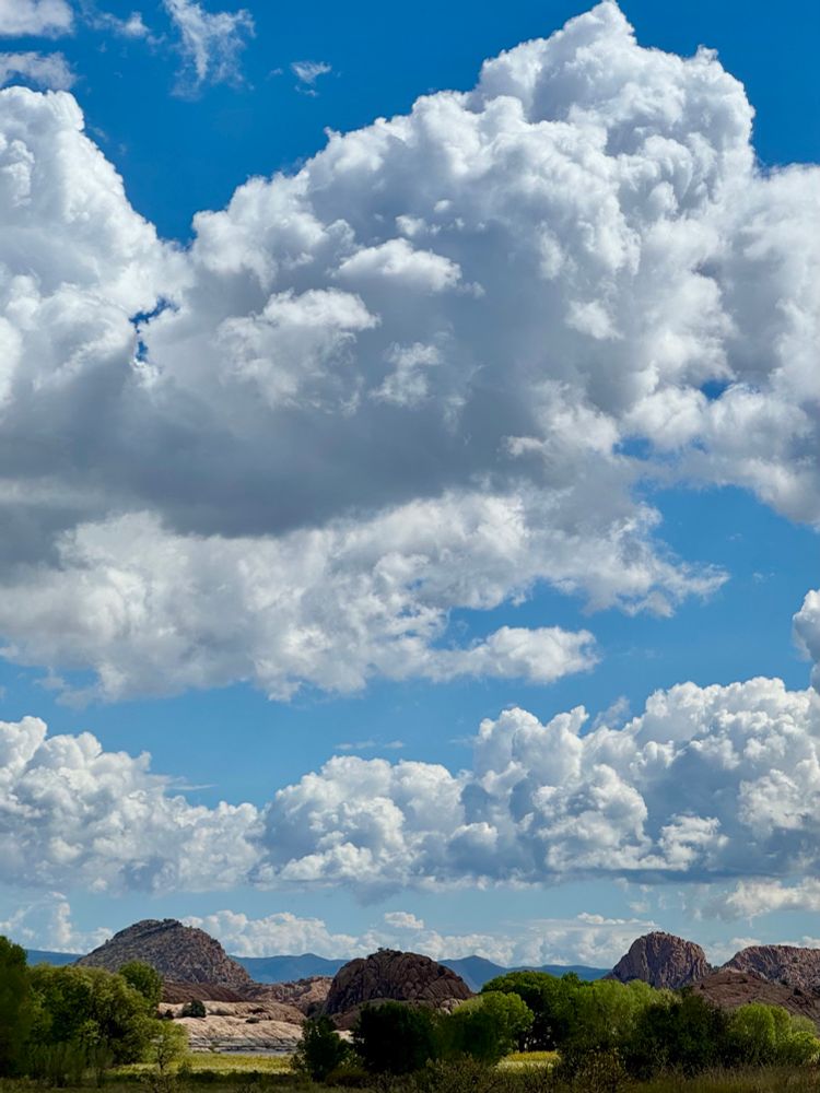 Granite Dells at Willow Lake near Prescott, Arizona under cloudy and blue skies. Shadows and bursts of sunshine highlight the outcroppings of granite, showing the different layers and depth in the landscape. Photo by T Jacobs. 