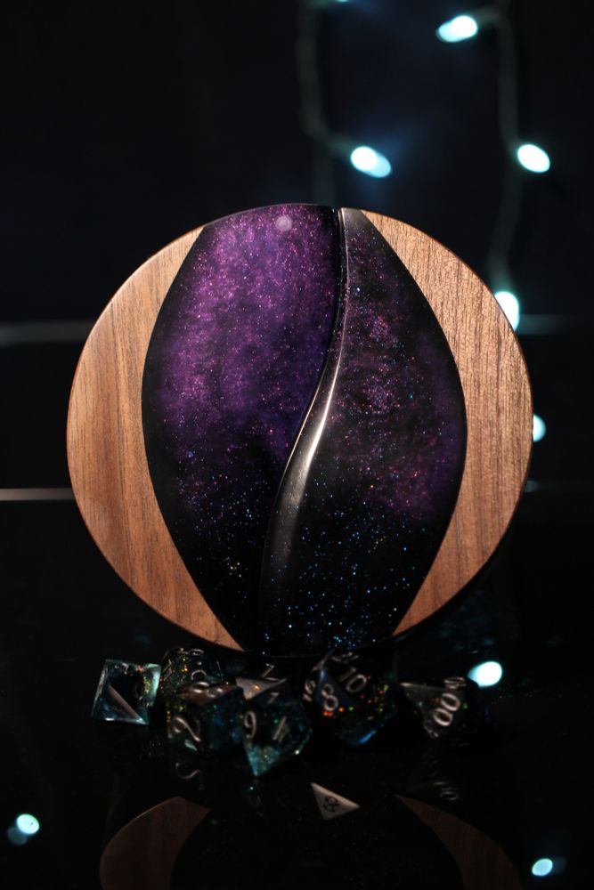 Round walnut dice box with an oval cutout filled with purple and black epoxy. 