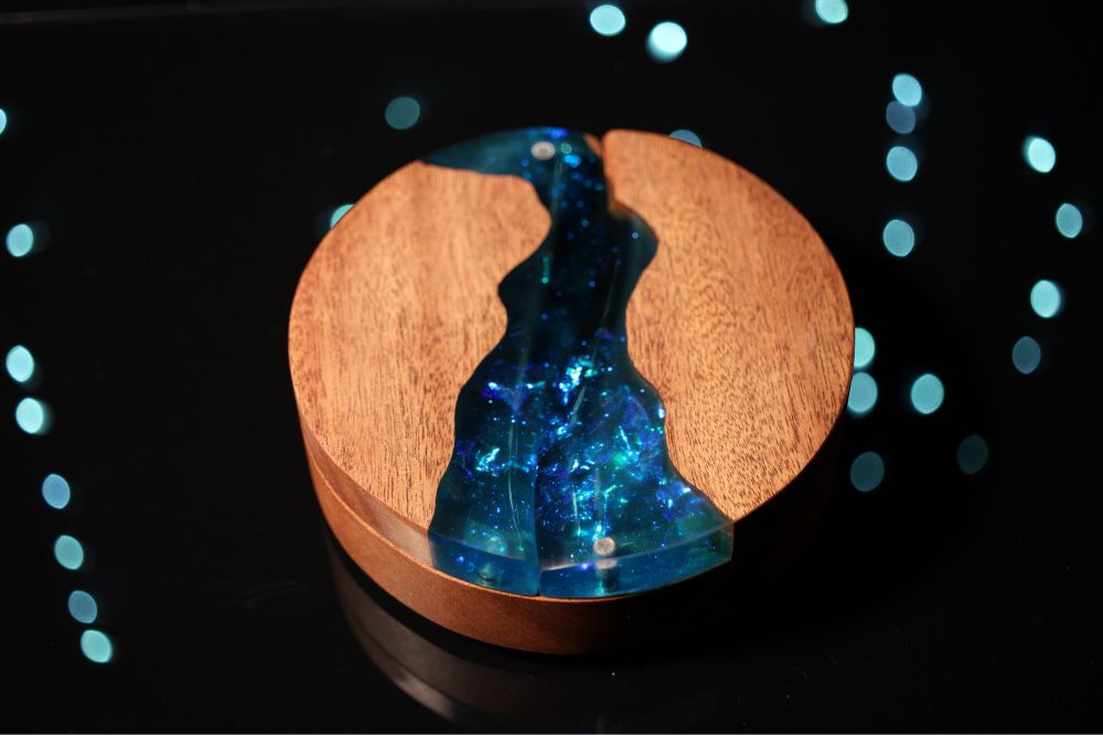 Round sapele dice box with a channel of iridescent blue resin running through the top with a hint of darkness at the top of the channel.
