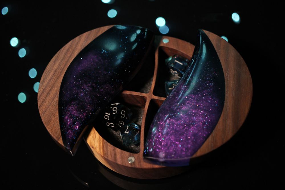 Round walnut dice box with an oval cutout filled with purple and black epoxy.  Shown open with four separate compartments.