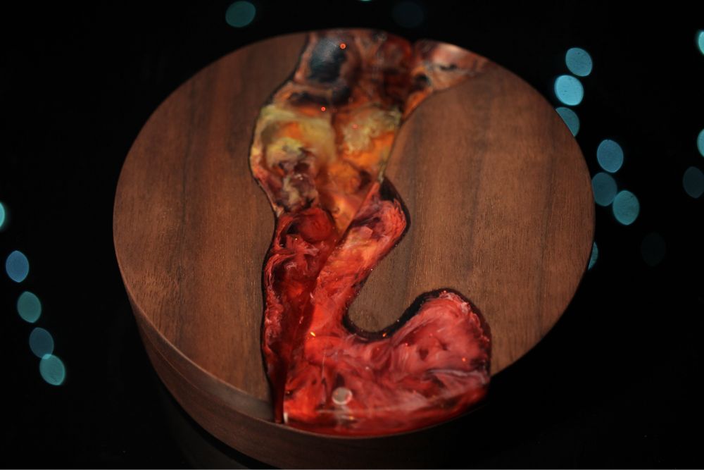 Round walnut dice box with a channel of red, orange, yellow, and black epoxy running through the top.