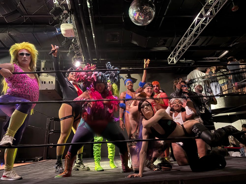 A group of drag performers posing together in a wrestling ring