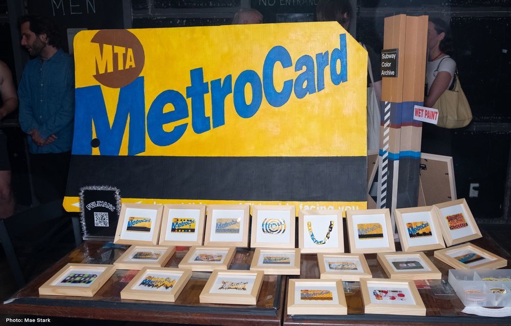 A large MetroCard made out of cardboard sits in front of other MetroCard art. Photo by Mae Stark.