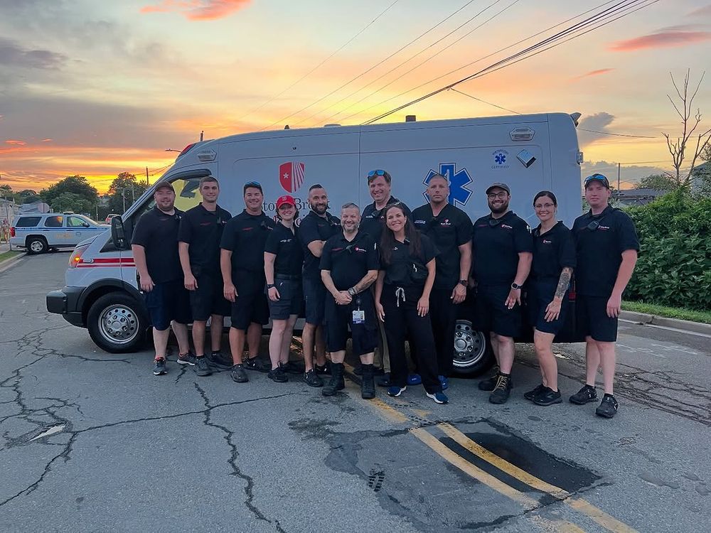 Group of paramedics standing in front of their ambulance at sunset.