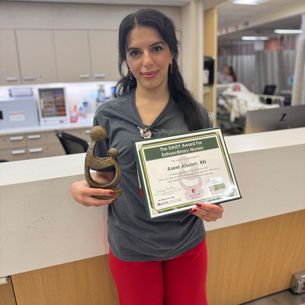 Person holding a trophy and The DAISY Award for Extraordinary Nurses certificate.