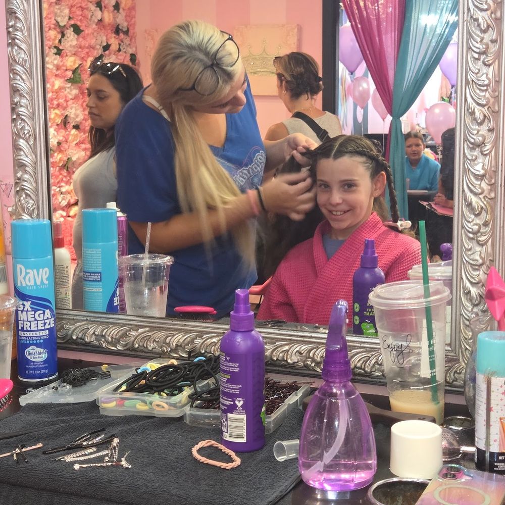 A person is getting their hair styled by a hairstylist in a salon, surrounded by beauty products and mirrors.
