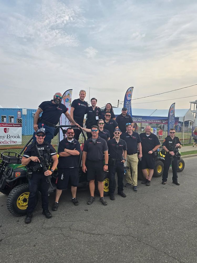 Group of security personnel standing and sitting on ATVs, wearing black uniforms, at a Stony Brook Medicine sponsored event.