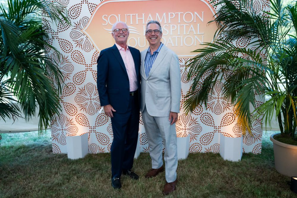 Two individuals smiling while standing in front of a Southampton Hospital Foundation backdrop.