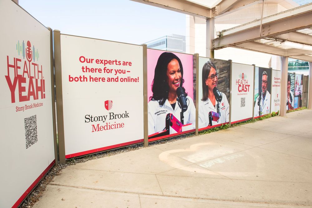 Promotional outdoor banners for Stony Brook Medicine featuring images of medical professionals and text stating, "Our experts are there for you – both here and online!" QR codes are also visible on the banners.