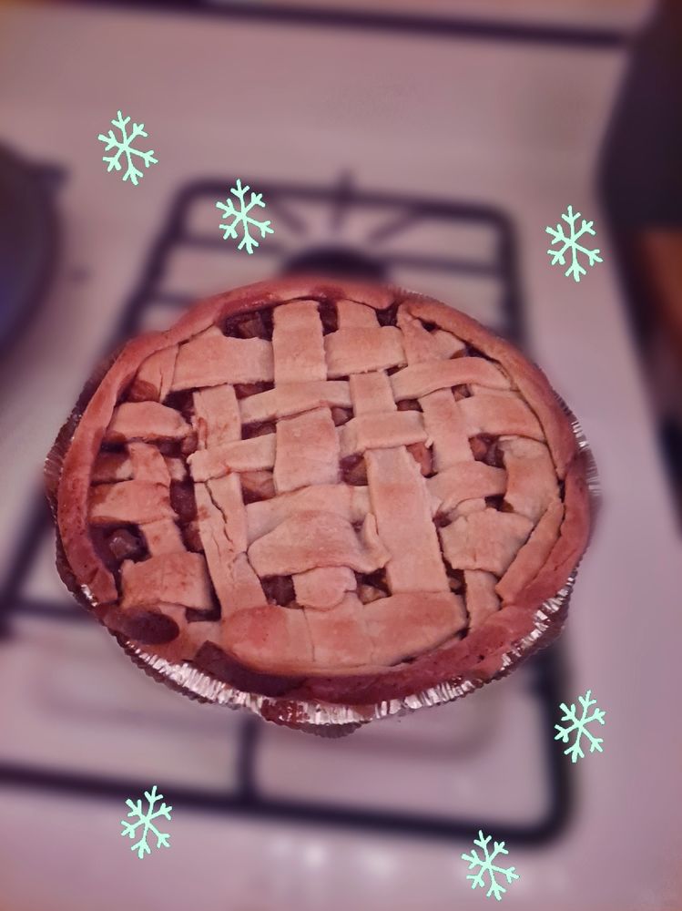 Apple pie displayed on stove top. A section of the side is possibly overcooked