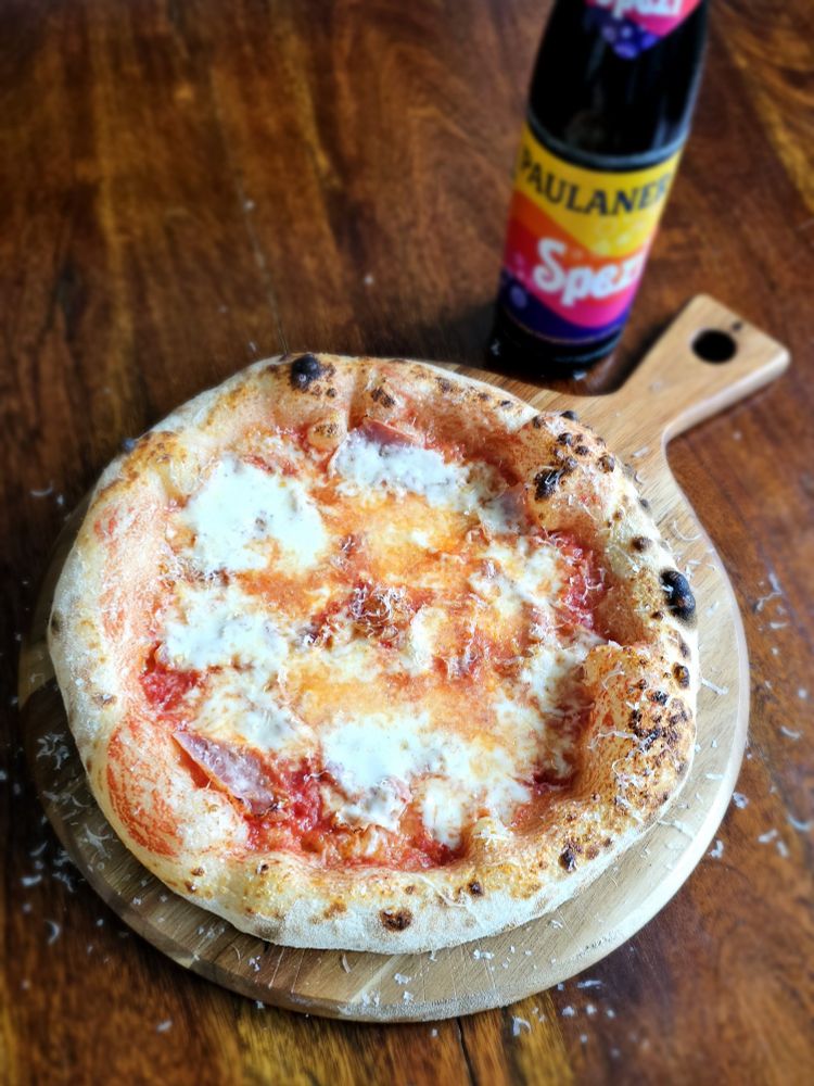 Bild einer unfassbar lecker aussehenden und vom Benutzer Baumwollhose selbstgemachten neapolitanischen Pizza Prosciutto mit einer Flasche Paulaner Spezi im Hintergrund 