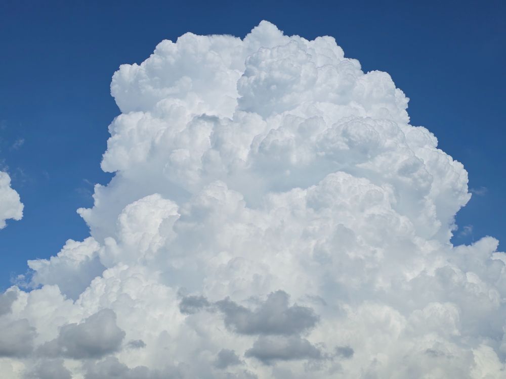 Large white fluffy cloud against bright blue sky.