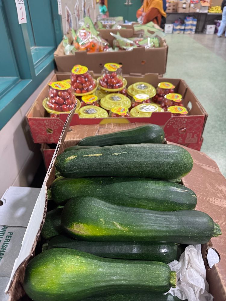 Boxes of zucchini, cherry tomatoes, and baby peppers on a table