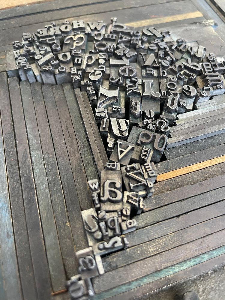 Tray with metal type set in an organic shape, held in place by pieces of wood