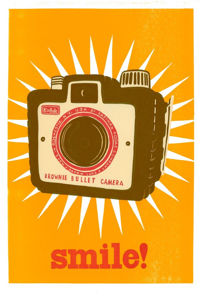 A vintage Kodak brownie camera with a Kodak yellow background. There’s a white burst like a flashbulb behind the camera. Text underneath reads “Smile”