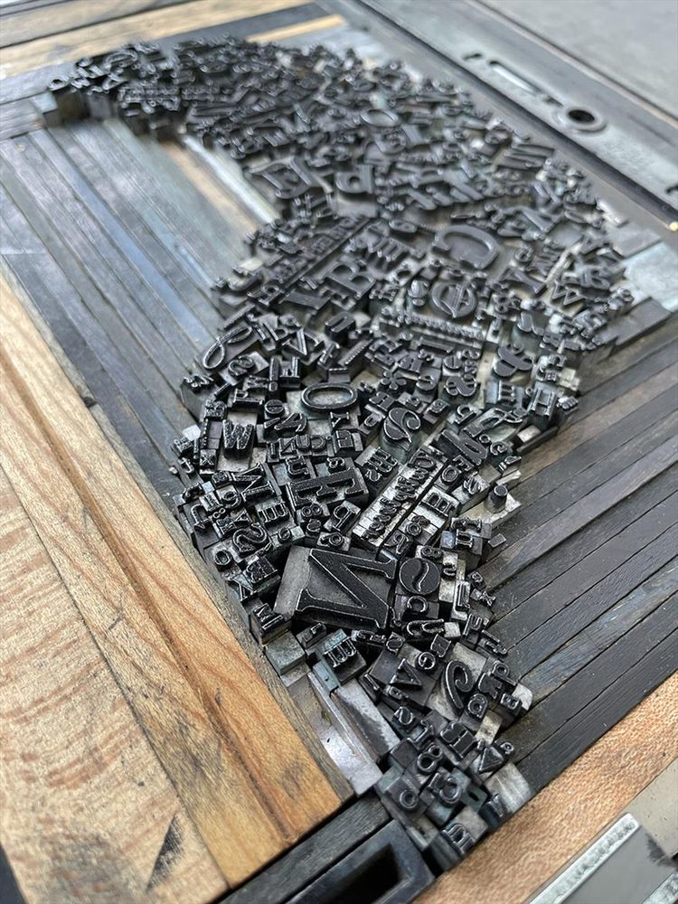 Tray full of metal type set in an organic shape, held in place by pieces of wood