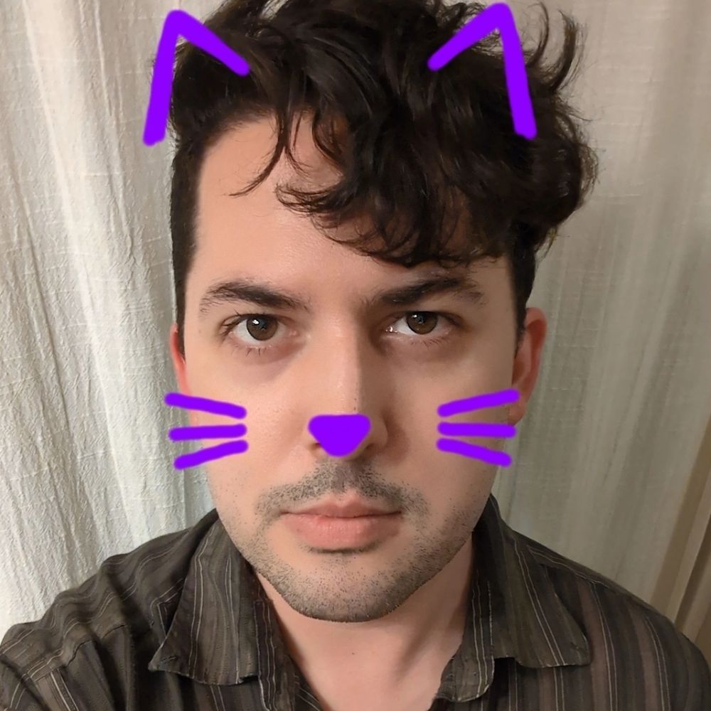 Man posing for a selfie with purple cat whiskers and ears drawn on his face 