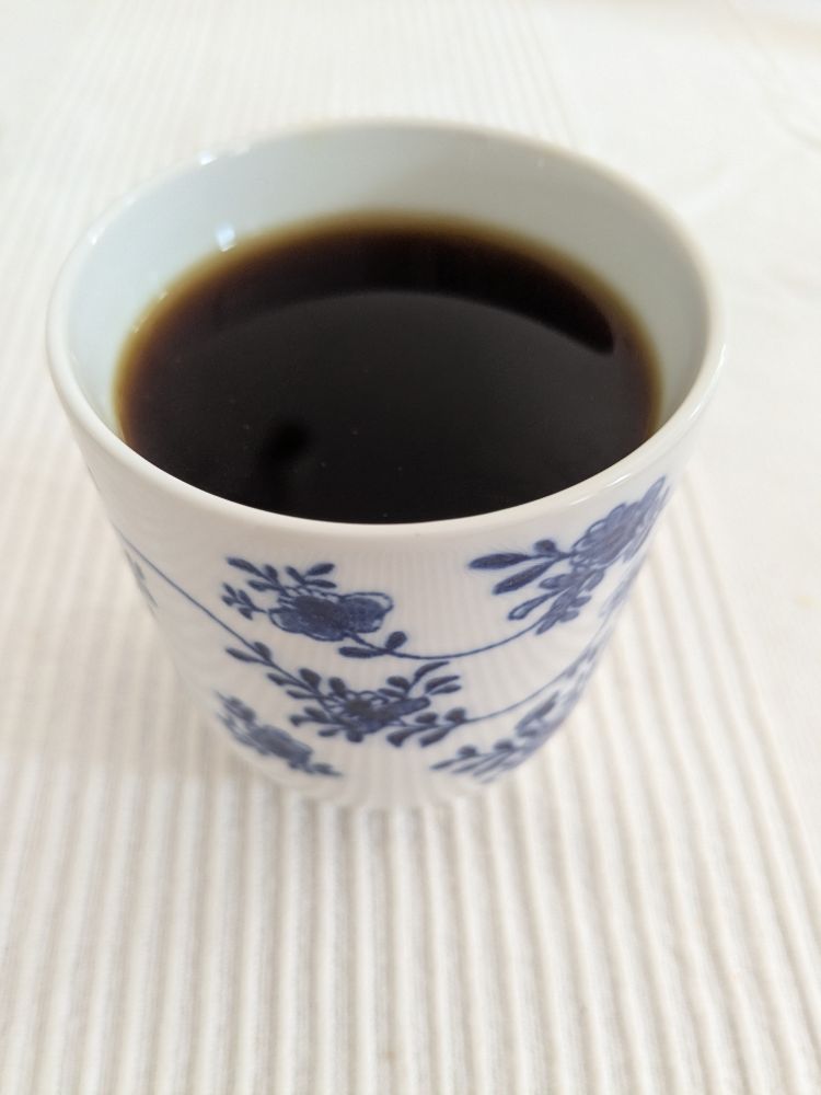 Filter coffee in a small bone china cup, white with a blue floral motif