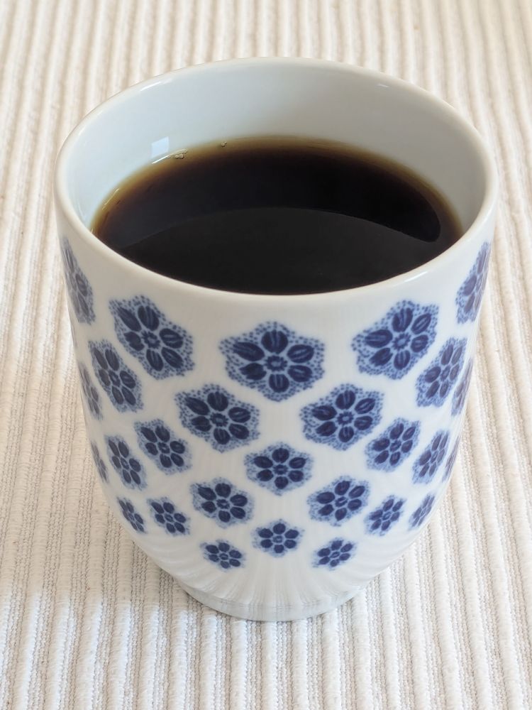 Filter coffee in a bone china cup, white with a blue floral motif.