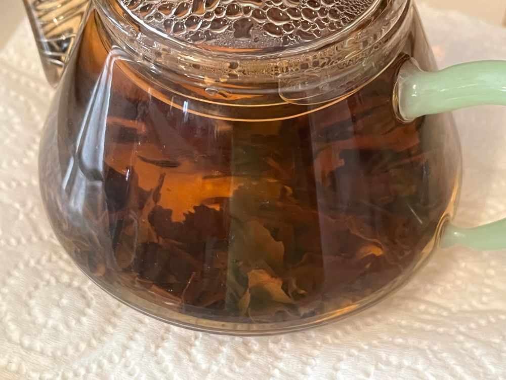 [ID: tea leaves in tea in a small glass tea pot. /end ID.]