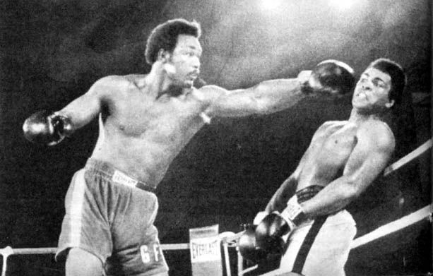 Photo of George Foreman trying to punch Muhammed Ali and missing the connect due to Ali using his rope-a-dope fighting style, which he leans against the ropes briefly to avoid a punch. 