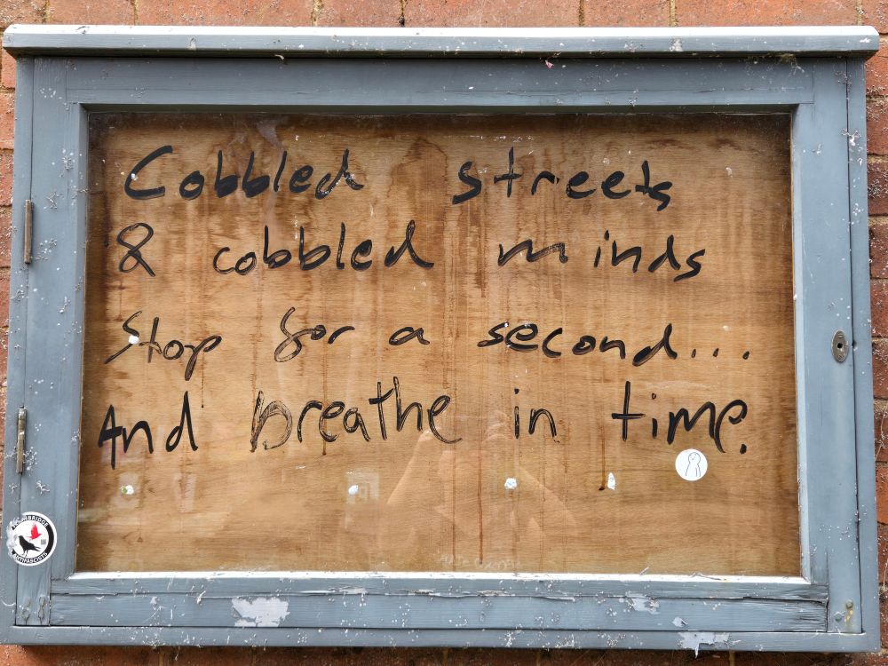 On an abandoned sign, a street poet has written "Cobbled streets & cobbled minds. Stop for a second...and breathe in time."