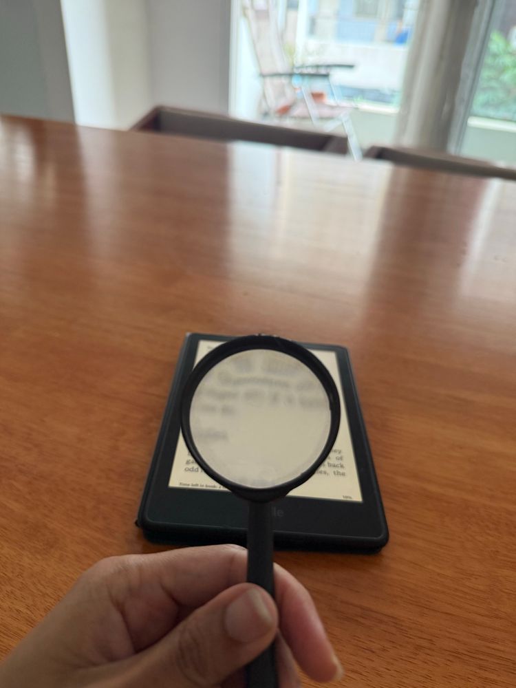 Magnifying glass held up to a kindle 