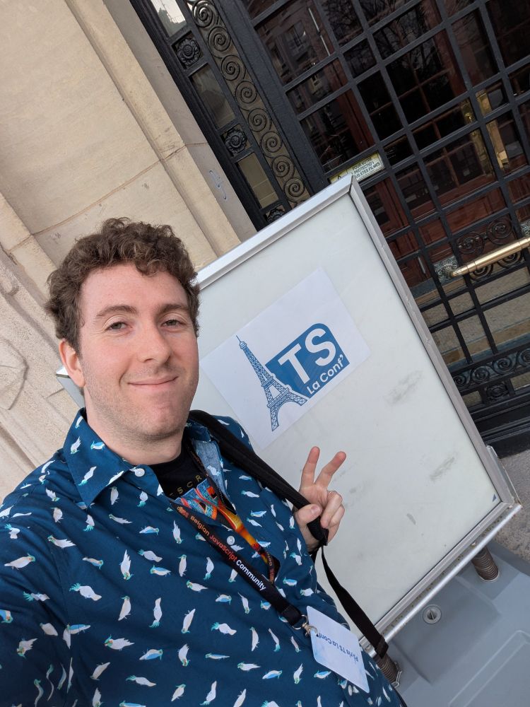 Smiling selfie wearing a collared shirt with birds above a Doom TypeScript shirt. behind me is the Paris TS conference logo on a piece of paper