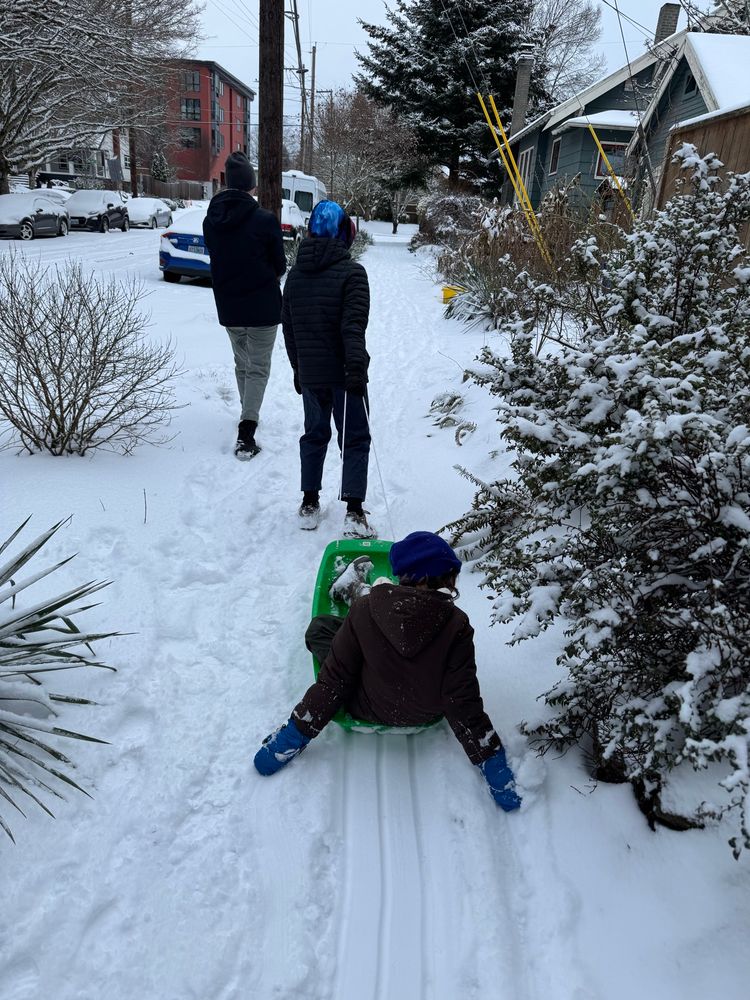My family in the snow. 8 year old is on a sled and 11 year old pulling the sled. 
