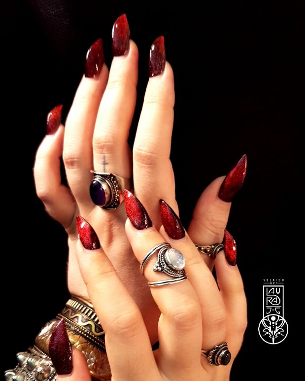 Una de las fotos sin retocar de la manicura roja con efecto ojo de gato. Las dos manos, superpuestas, se muestran altamente enjoyadas