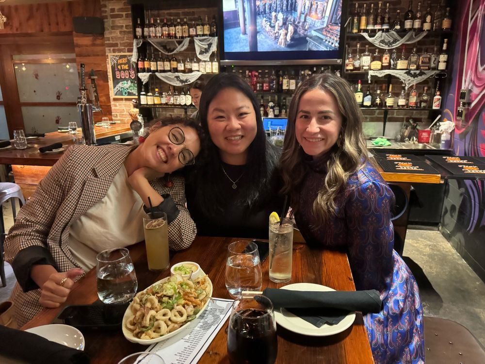 Three women sitting in a restaurant table smiling at the camera