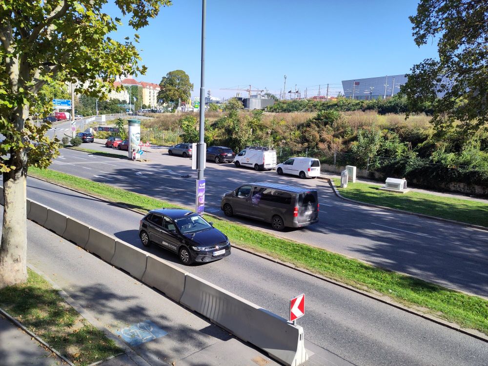 Im Vordergrund die Eichenstraße mit einer Protected Bike Lane. Links die Einmündung in den Gürtel. Mittig eine Brache die mit verschiedenen Pflanzen überwuchert ist, inzwischen ziemlich herbstlich gefärbt. Im Hintergrund die Bahnstrecke der Südbahn und Gebäude der ÖBB des Standortes Matzleinsdorferplatz.